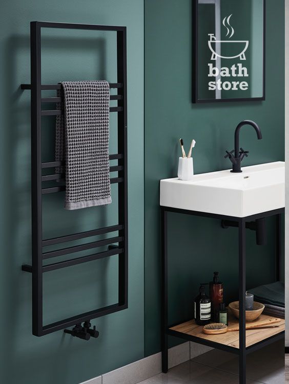 a bathroom with green walls and a black towel rack next to a white porcelain sink