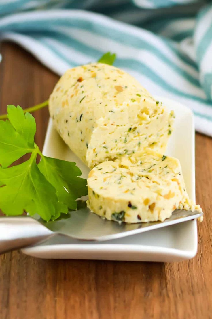 two pieces of bread on a white plate next to a green leafy garnish