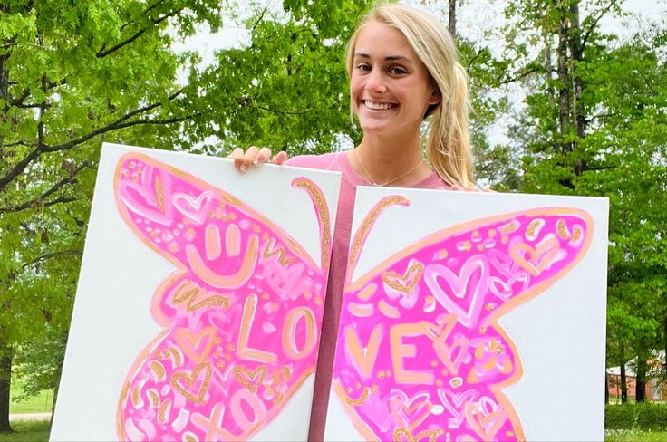 a woman holding up a large butterfly sign in front of her face with the words love written on it