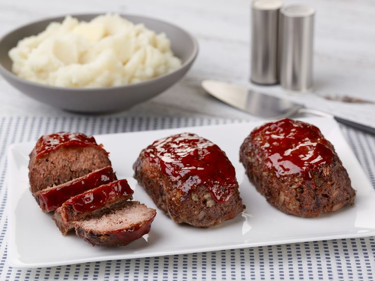 meatloaf on a plate with mashed potatoes and gravy in the background