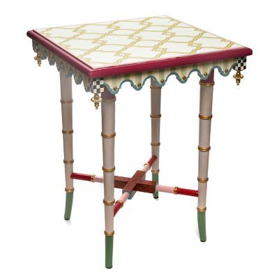 a small table with an ornate design on it's top and legs, painted in white