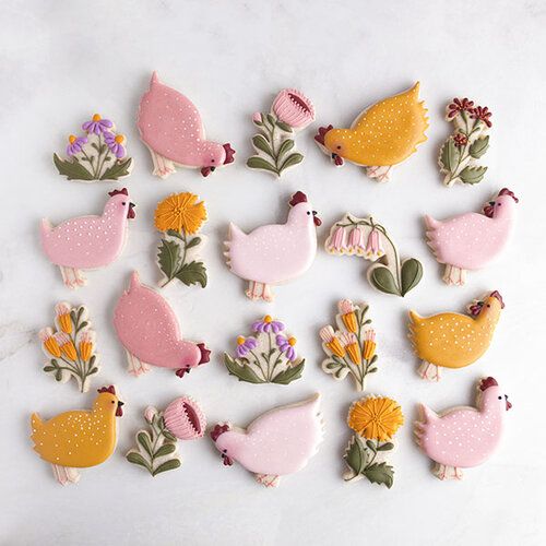 some pink and yellow decorated cookies on a white table with flowers, birds and leaves