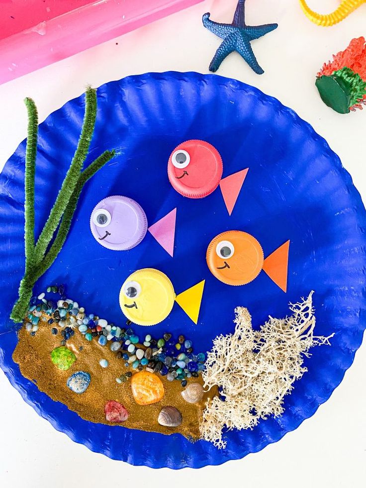 a paper plate with fish and seaweed on it, surrounded by other crafting materials