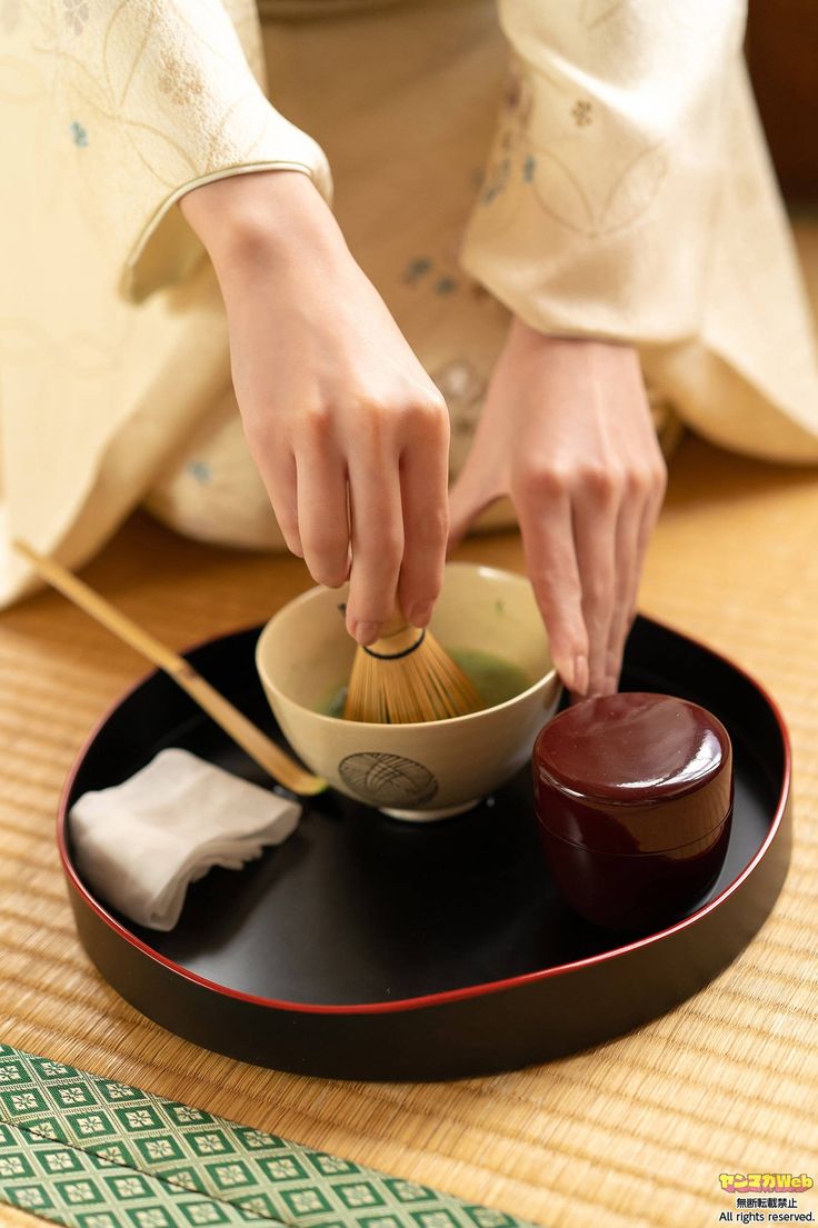 a woman is holding a wooden whisk over a bowl on a black plate