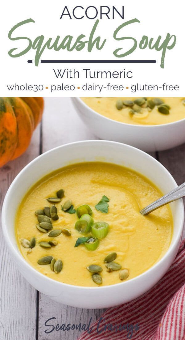 two white bowls filled with squash soup on top of a wooden table next to pumpkins