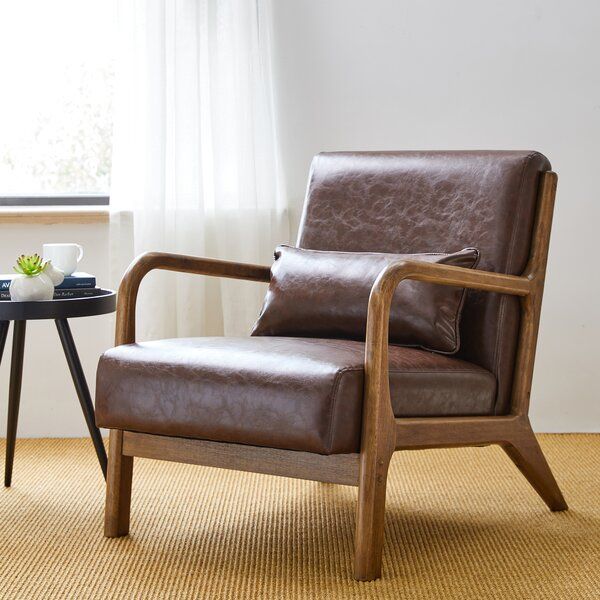 a brown leather chair sitting in front of a window next to a table with a cup on it