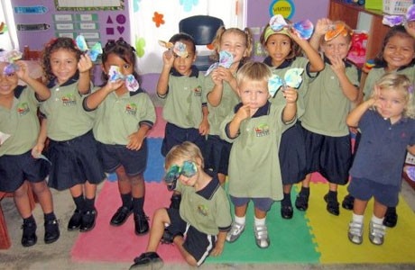 a group of young children standing next to each other in front of a classroom wall