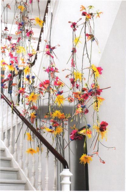 colorful flowers are growing on the side of a stair case in front of a white railing