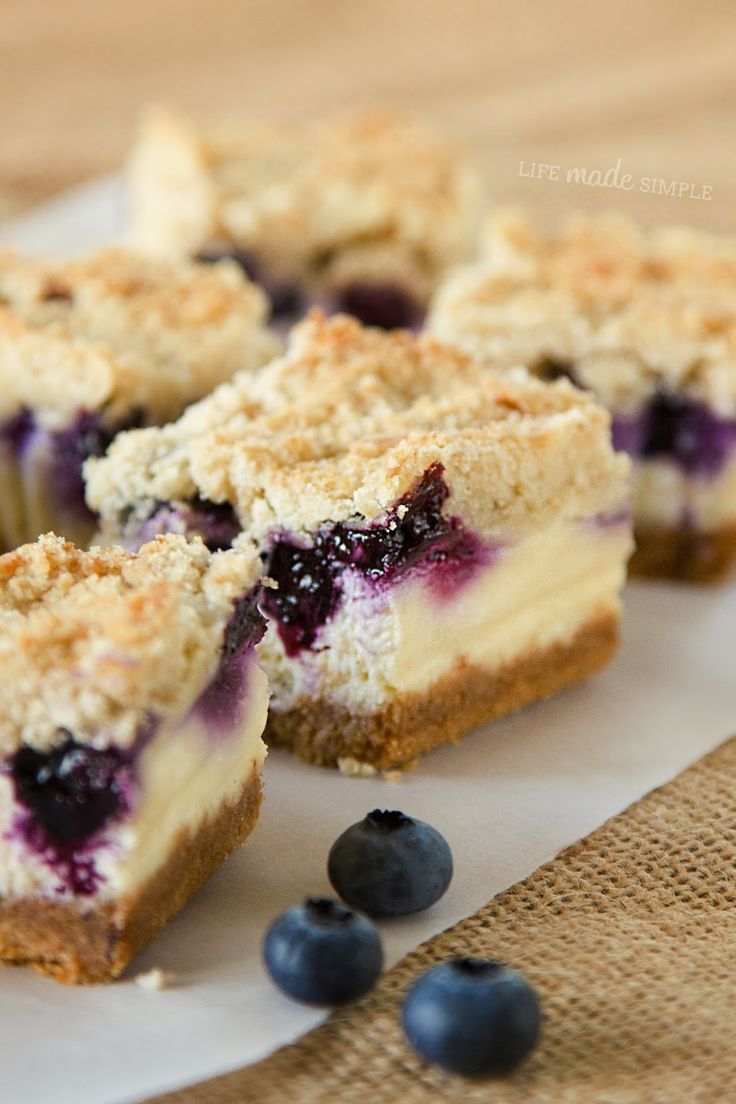 blueberry cheesecake with crumbs cut in half on top of a piece of parchment paper