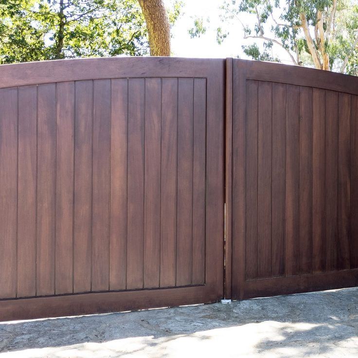 a brown wooden fence is shown with trees in the background