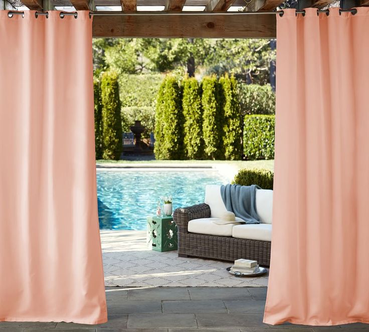 an outdoor patio with orange curtains next to a swimming pool