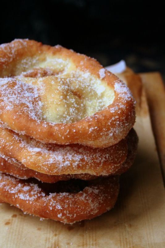 a stack of sugar covered donuts sitting on top of a wooden cutting board