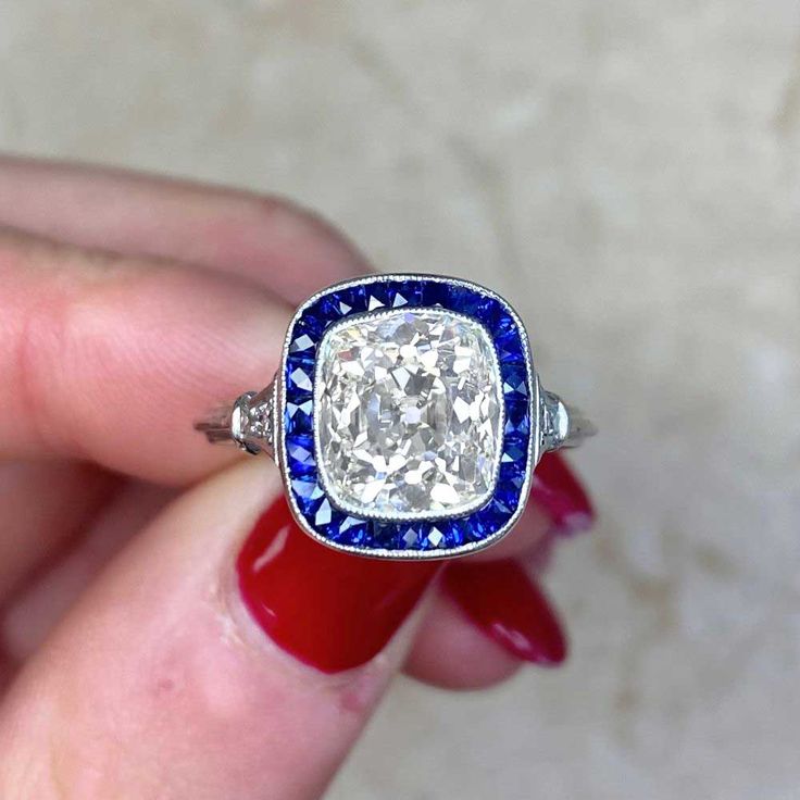 a woman's hand holding an old - fashioned diamond and blue sapphire engagement ring