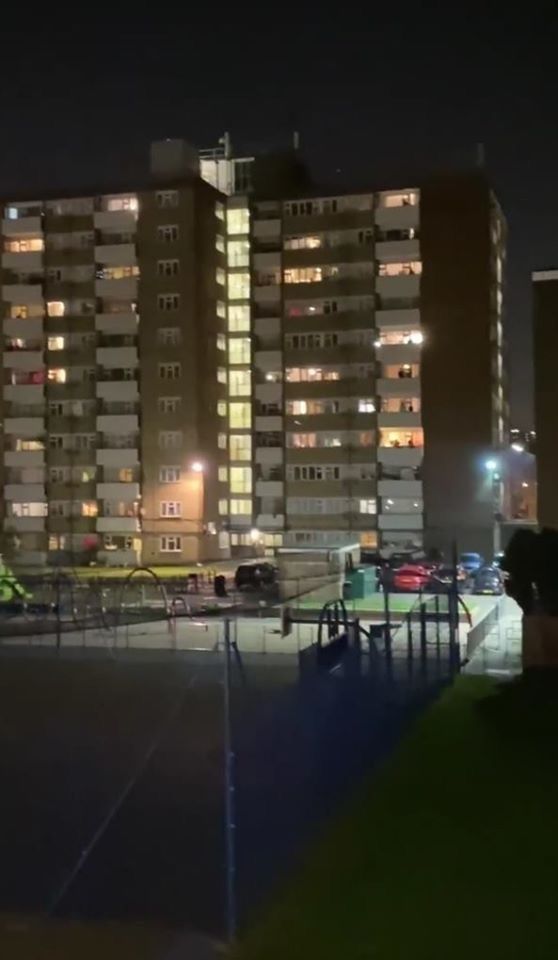 an apartment building at night with cars parked in the parking lot and lights lit up