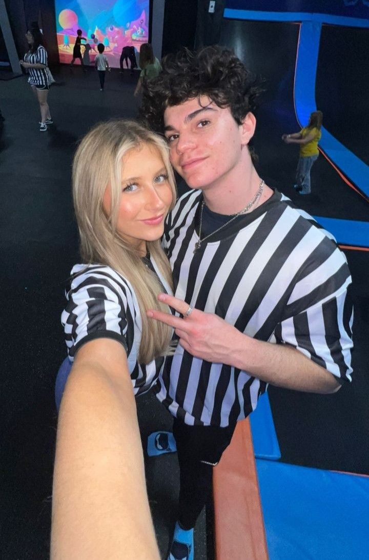 a man and woman taking a selfie in front of a video game booth at an amusement park