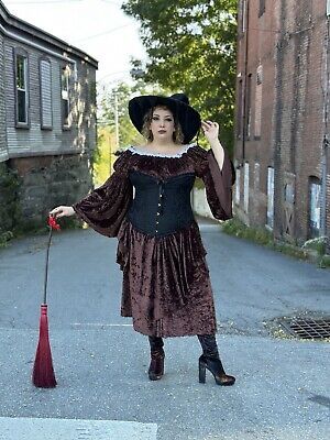 a woman in a dress and hat is holding a red umbrella while standing on the street