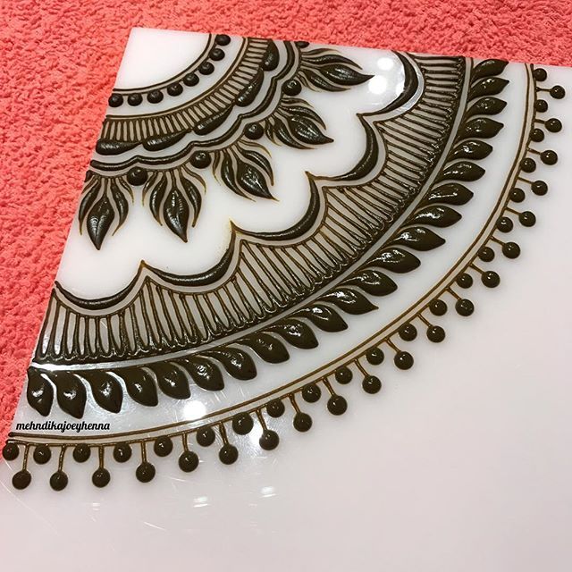 a white plate with black designs on it sitting on a pink towel next to a red rug