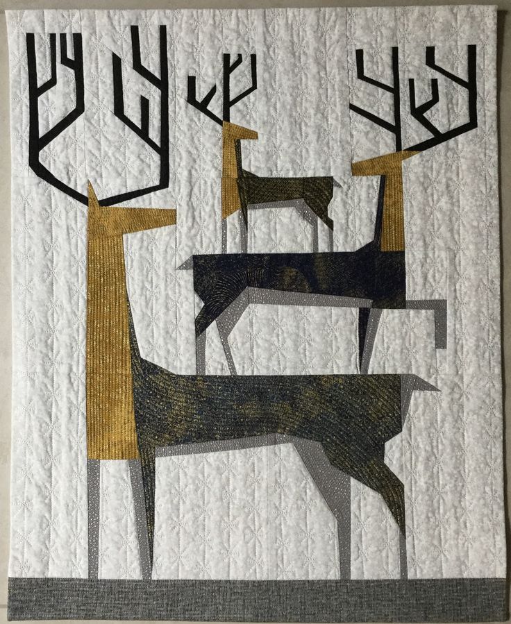 a quilted wall hanging with deer and trees on it