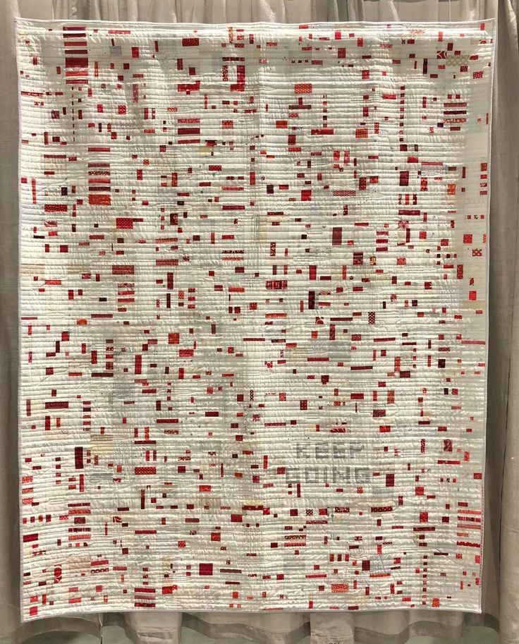 a white and red quilt hanging on a wall