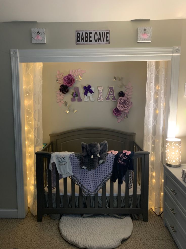 a baby's crib is decorated with purple flowers and lights for the nursery