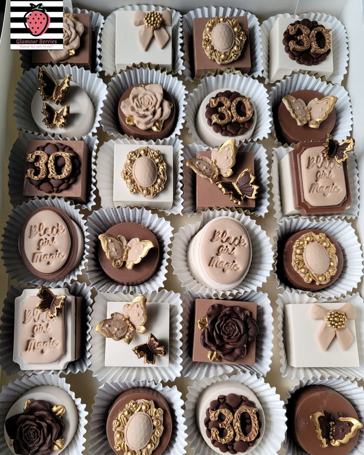 a box filled with lots of chocolates covered in gold and white frosted icing