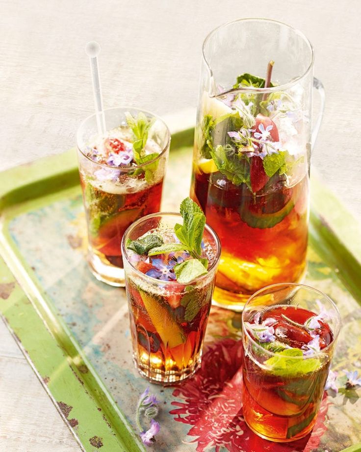 three glasses filled with different types of drinks on top of a green serving platter