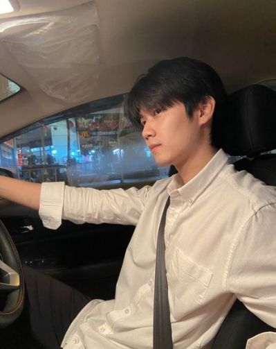 a man sitting in the driver's seat of a car with his hand on the steering wheel