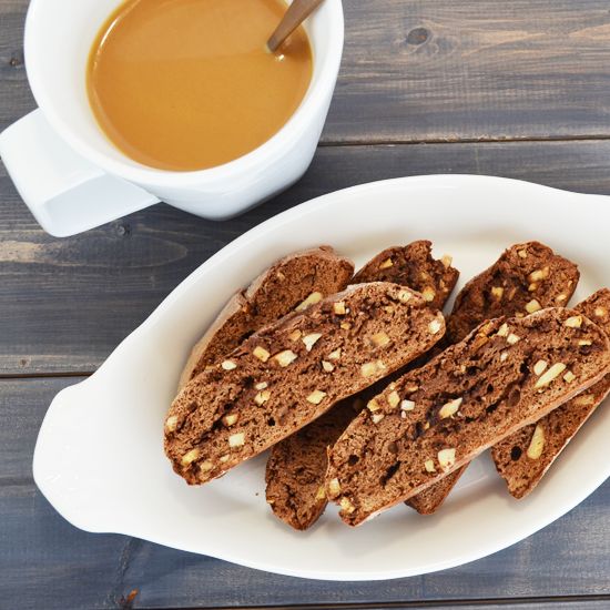 several pieces of bread on a white plate next to a cup of coffee and saucer