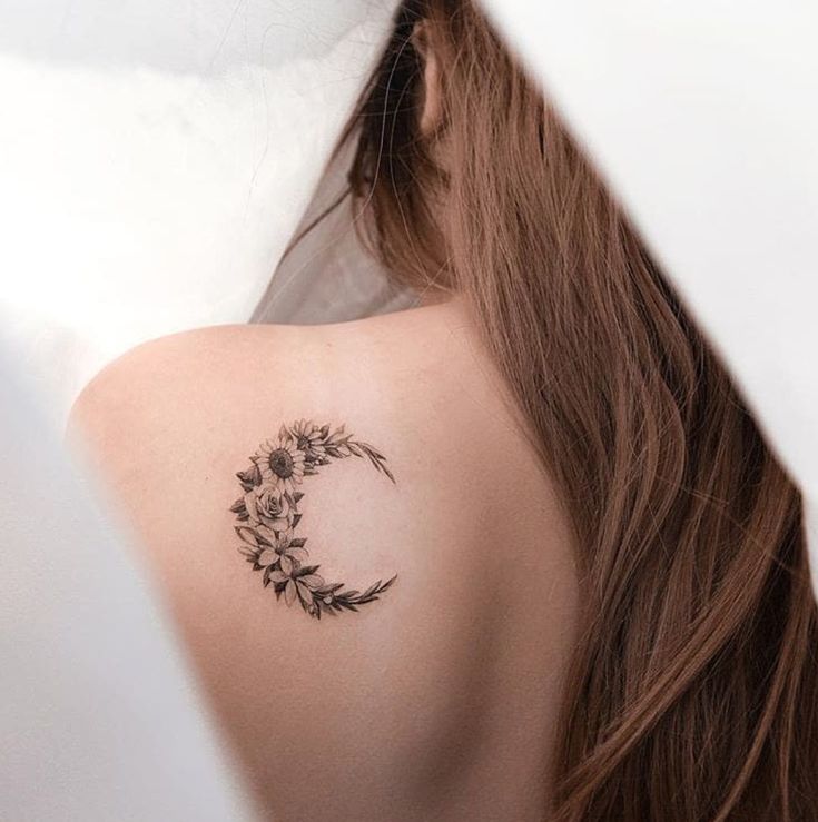 a woman's back shoulder with a small flower tattoo on the left side of her upper arm