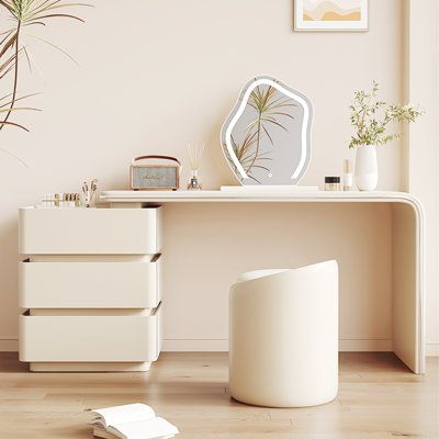 a white desk with drawers and a mirror on the wall next to a potted plant