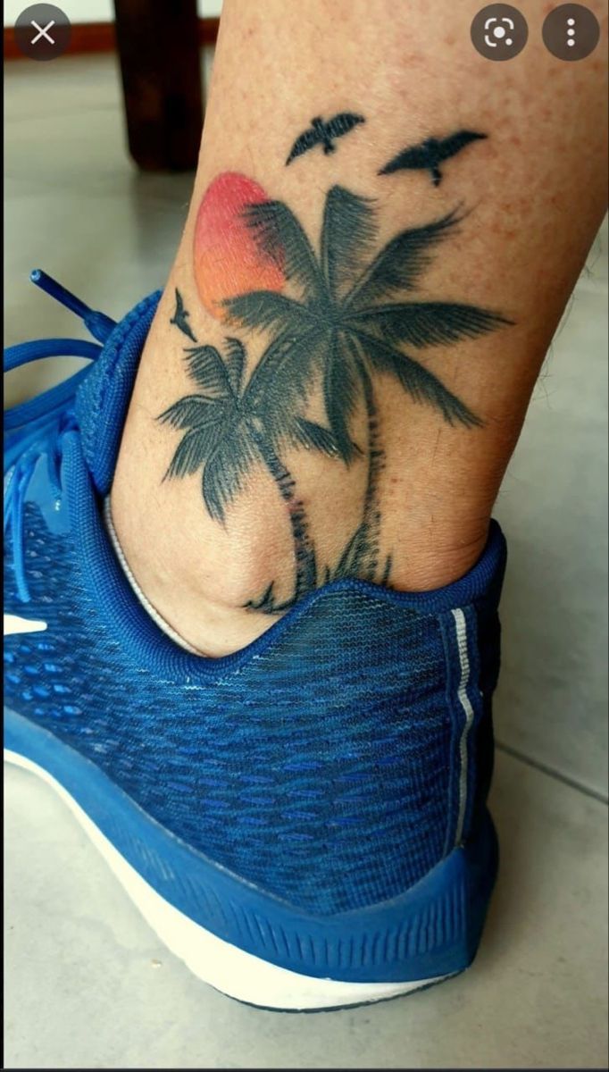 a person's foot with a palm tree and birds tattoo on the bottom of it