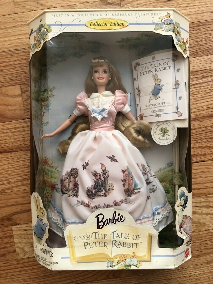 a barbie doll in a box on a wooden table with an advertisement for the tale of peter rabbit