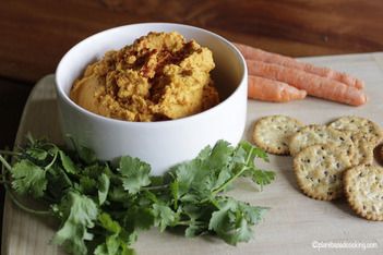 carrots and crackers on a cutting board next to a bowl of hummus