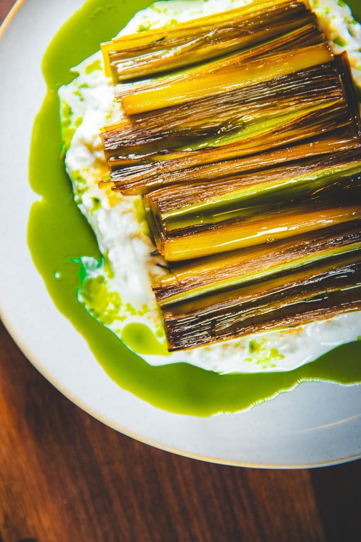 a white plate topped with food on top of a wooden table next to a green sauce