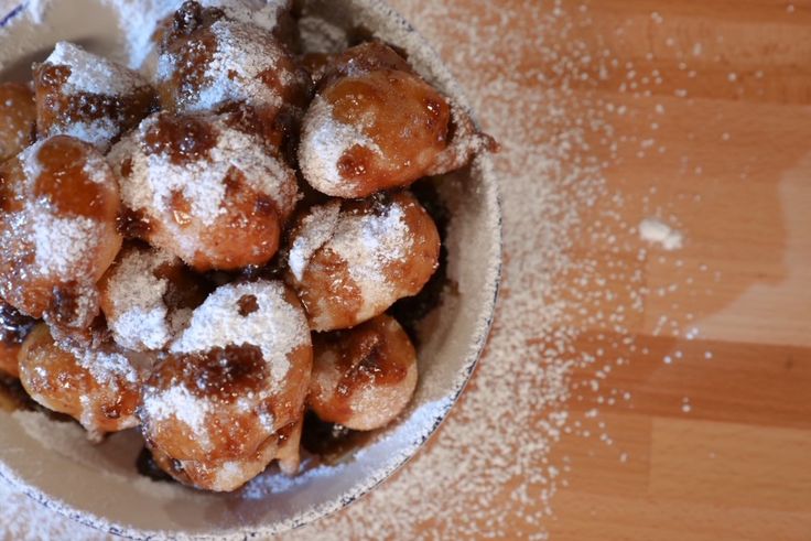 powdered sugar covered donuts in a white bowl