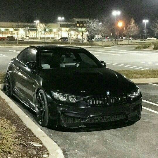 a black car is parked on the side of the road in front of an empty parking lot