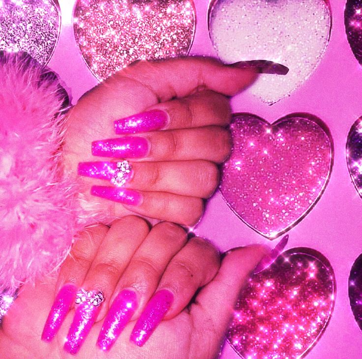 a woman's hand with pink and purple glittered nails next to heart shaped decorations