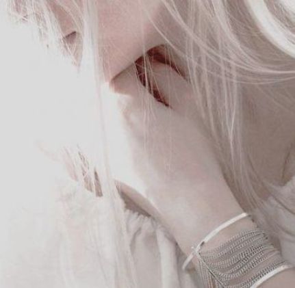 a close up of a person with white hair and bracelets on her wrist, looking to the side