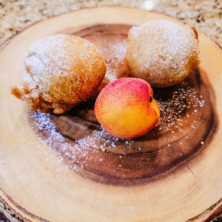 three pastries on a plate with powdered sugar sprinkled around them and an apple