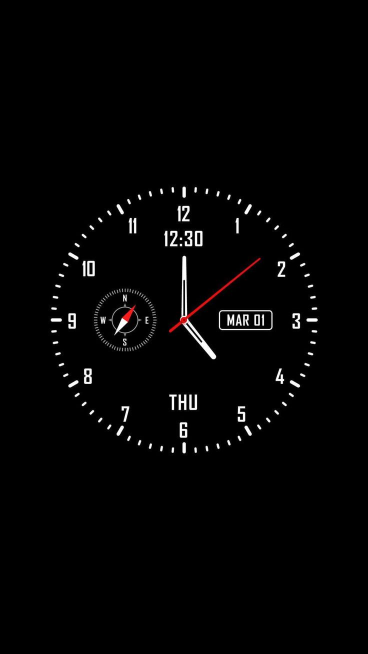 a black clock with red hands and numbers on the face is lit up in the dark