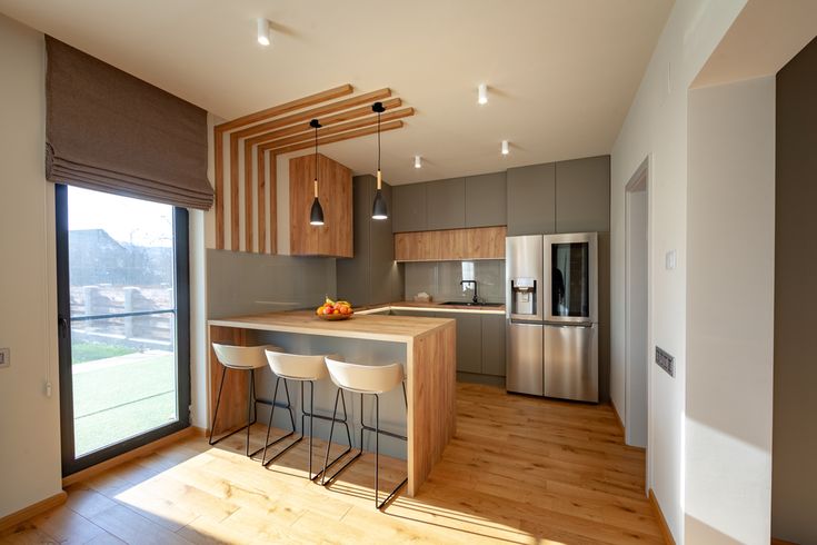 a kitchen with wooden flooring and stainless steel appliances in the middle of it, next to a sliding glass door that leads to an outdoor deck