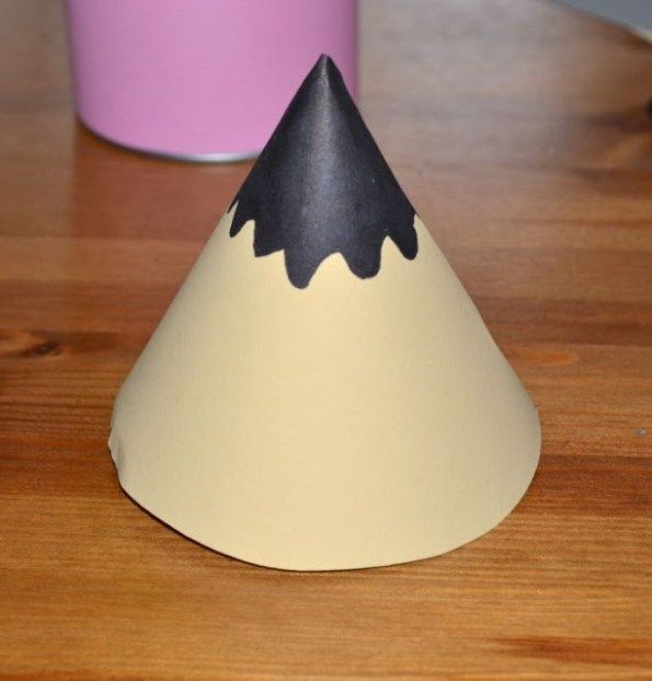 a black and white paper cone sitting on top of a wooden table next to a pink cup