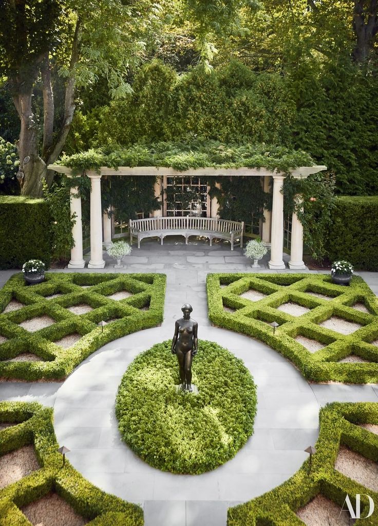 a garden with hedges and a statue in the center