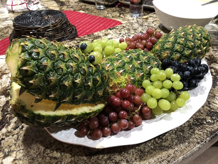 grapes, pineapples and other fruit are arranged on a plate in the kitchen