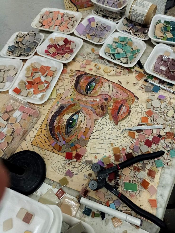 a table topped with lots of different types of mosaics and paint on paper plates