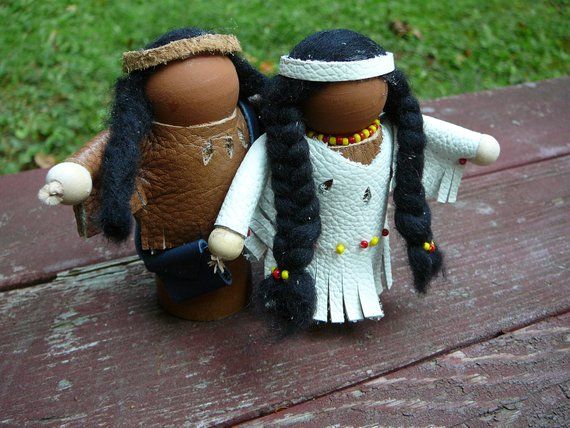 two dolls sitting next to each other on a wooden table in front of some grass