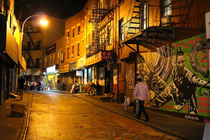 a city street at night with people walking on the sidewalk