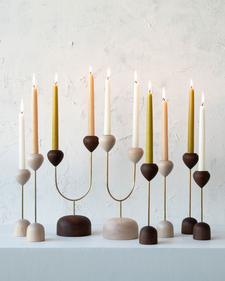 a group of candles sitting next to each other on top of a table in front of a white wall