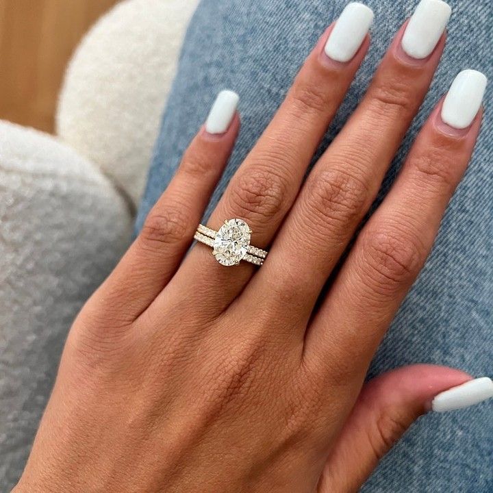 a woman's hand with white manicured nails and a diamond ring