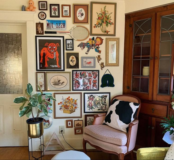 a living room filled with lots of framed pictures on the wall next to a chair